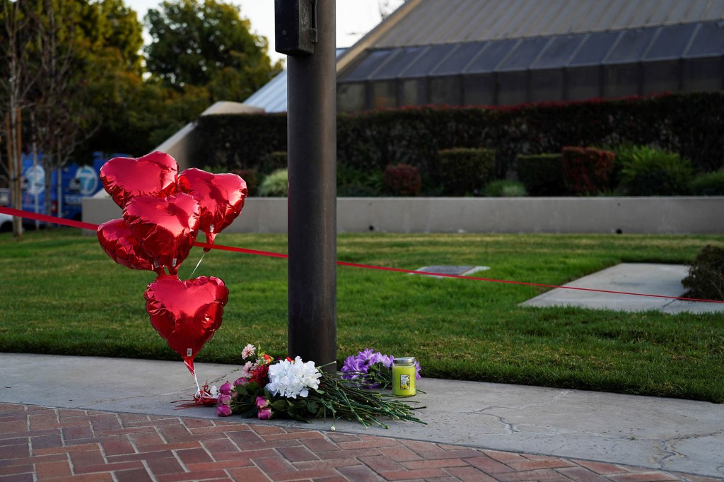Flowers and heart balloons are left near the scene of a shooting.